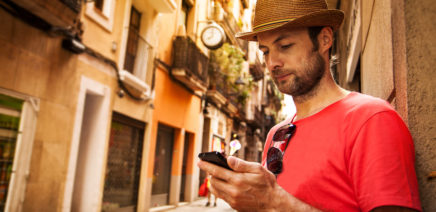 Man on phone in red tshirt and sun hat