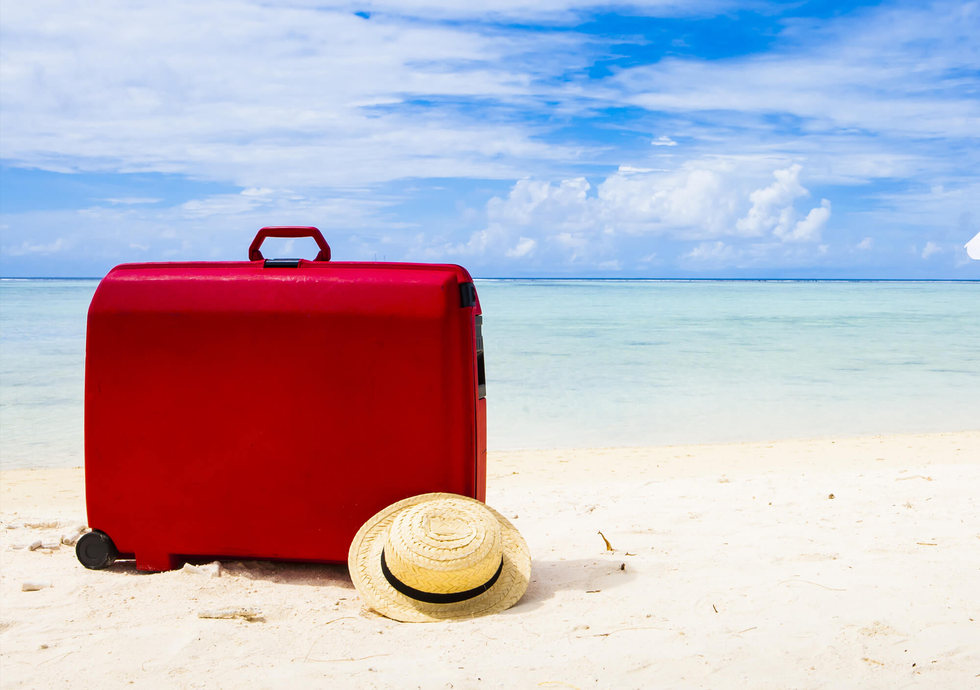 Red suitcase on beach